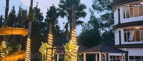 A pool area with a hot tub, palm trees, and a covered seating area with people.