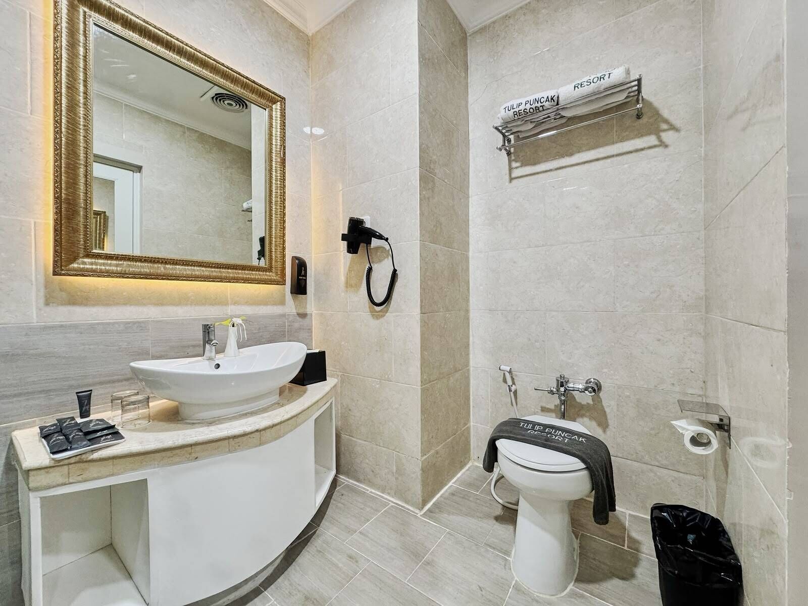 Ein modernes Badezimmer mit großem Spiegel, Waschbecken, Toilette und Handtuchhalter.