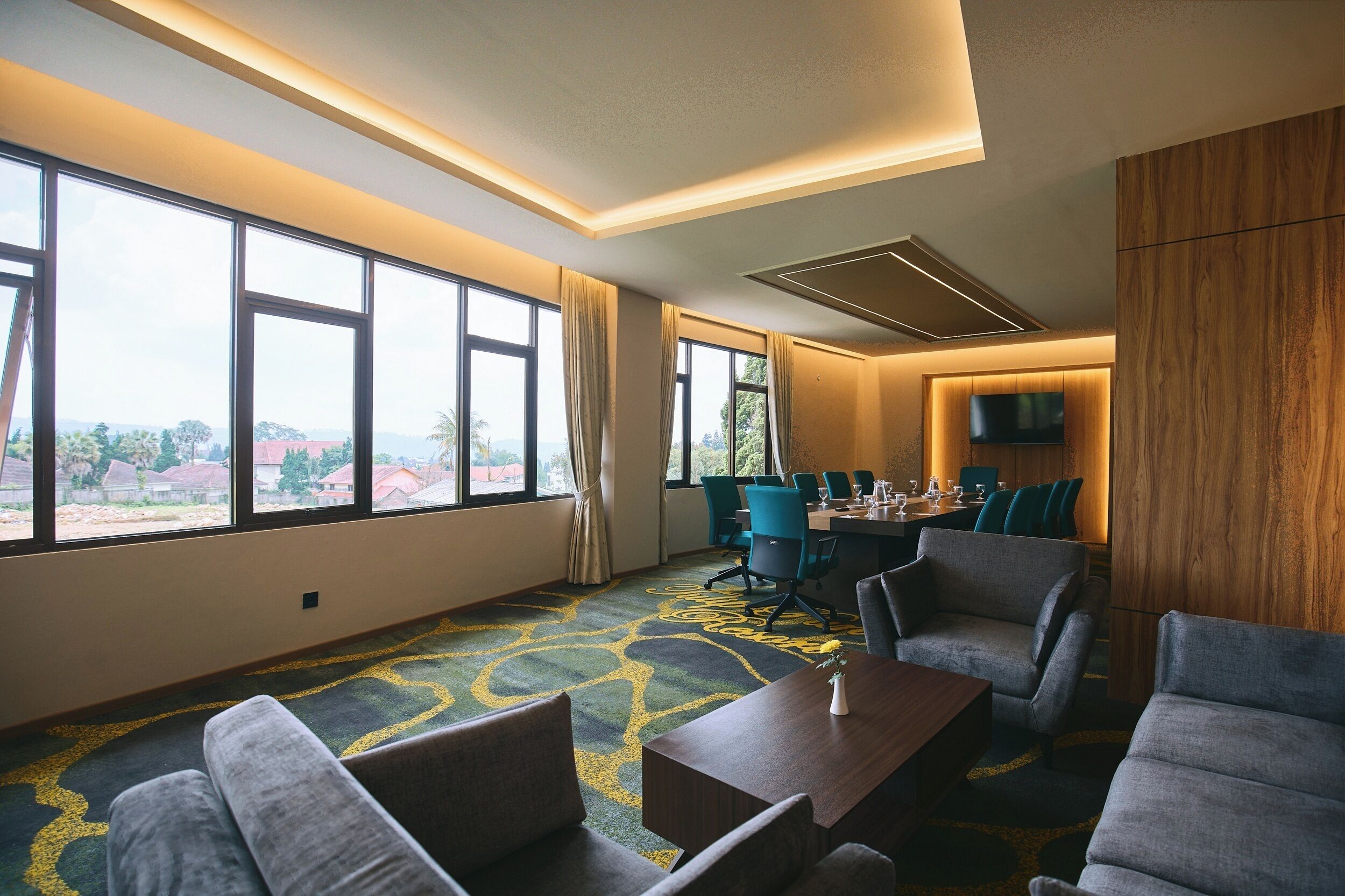 A hotel room with large windows, a conference table, and modern furniture.