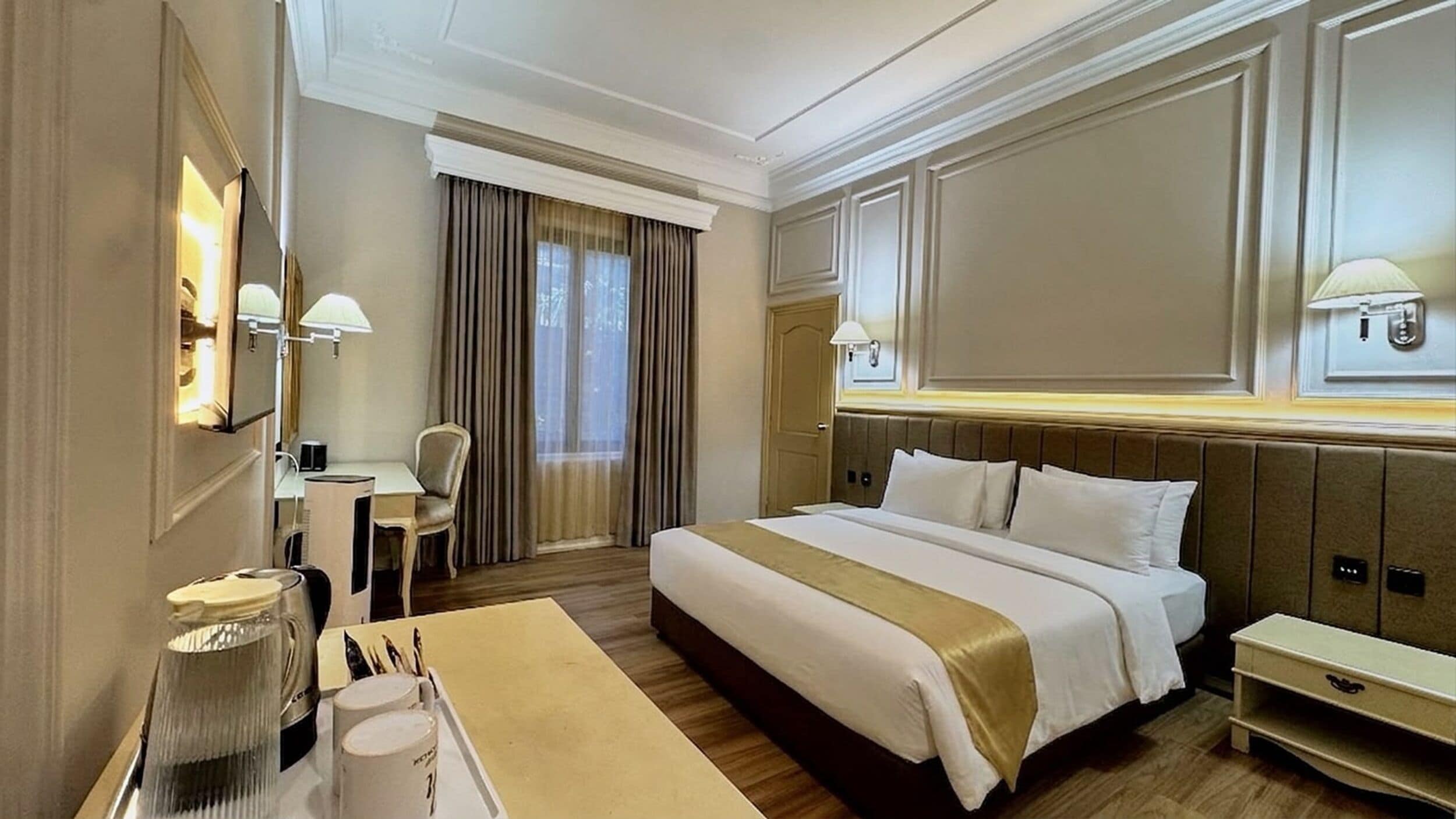 A hotel room with a large bed, bedside tables, a desk, and a chair.
