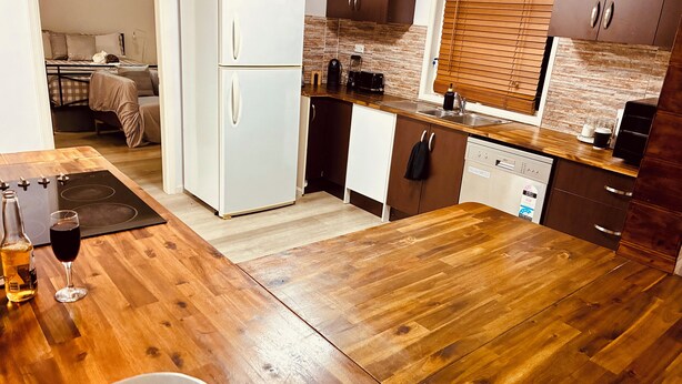 A compact kitchen with a refrigerator, stove, and wooden flooring.