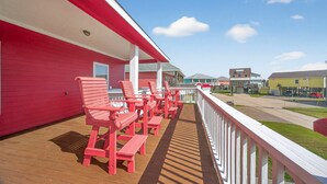 Un edificio rosso con veranda in legno e sedie rosse.