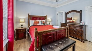 Una camera da letto con un letto in legno, lampade sui comodini, una panca, una cassettiera e una ventola a soffitto.