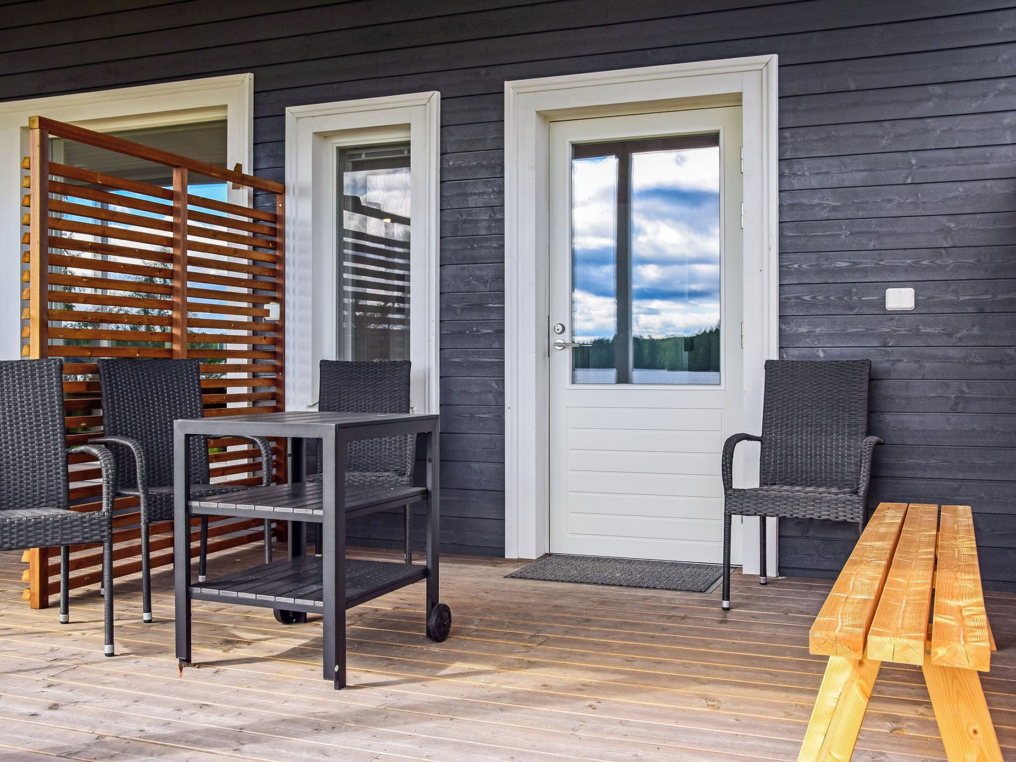 A covered outdoor seating area with a table and chairs, a wooden bench, and a sliding door.