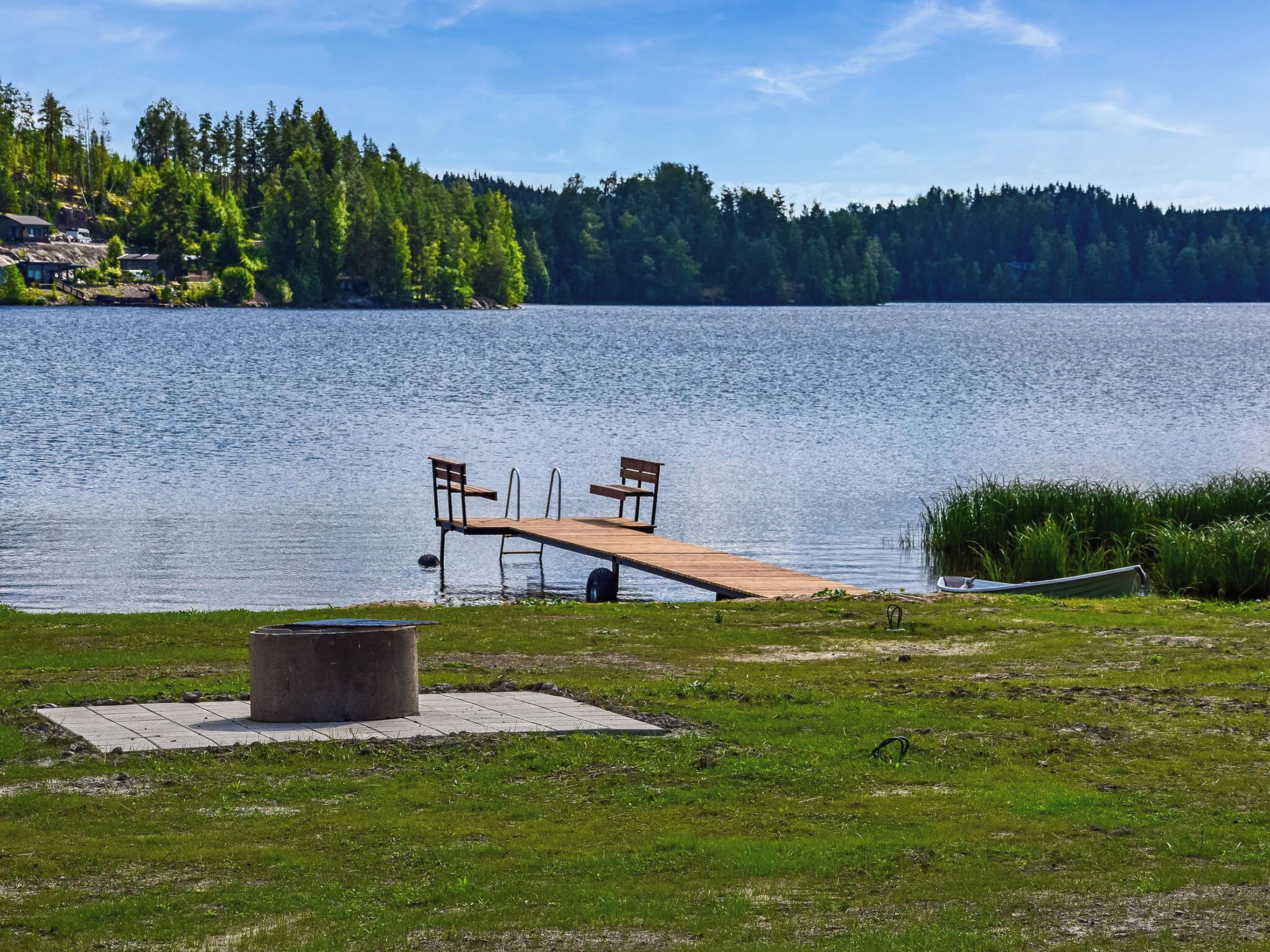 A lakeside dock with benches and a fire pit.