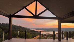 Un molo di legno con vista su un lago e montagne al tramonto.