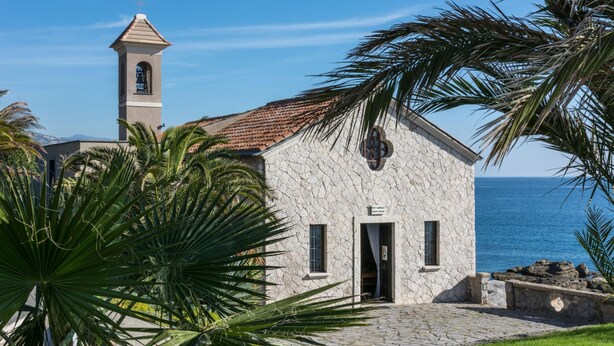 A stone building with a bell tower, a door, and a window.