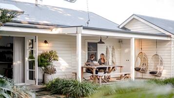 A house with a covered porch, a dining table, and hanging chairs.