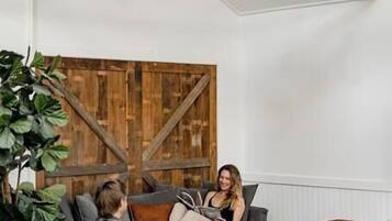 A cozy living room with a large wooden wall, a brown leather sofa, and a dining table.