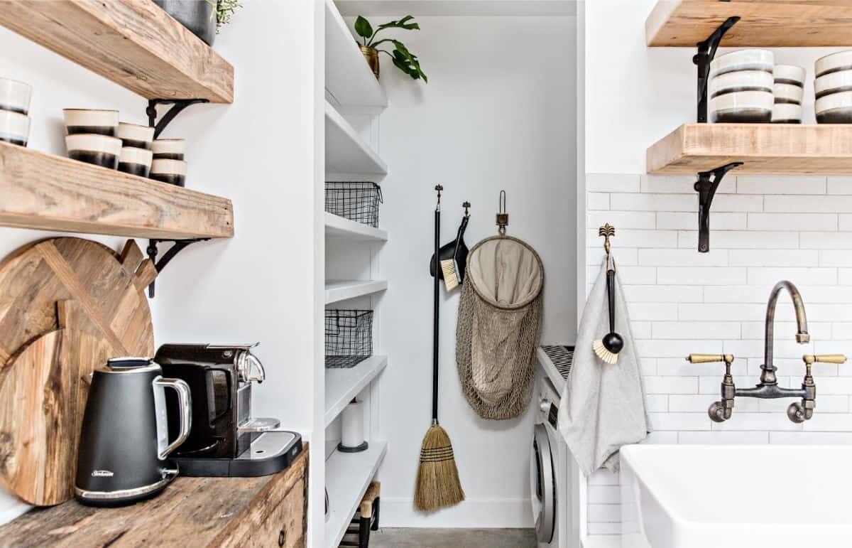 A modern kitchen with wooden shelves, a coffee maker, and a hanging broom.