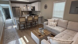 A modern living room with a sofa, coffee table, and a dining area with chairs.