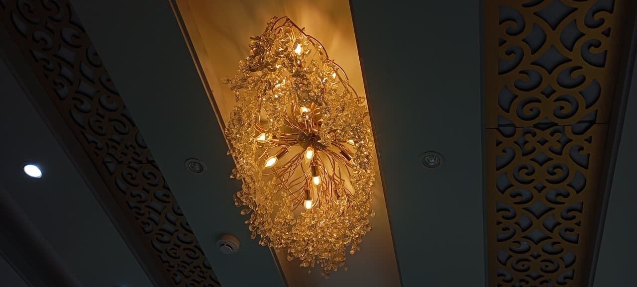 A chandelier with multiple light bulbs hanging from a decorative metal frame.