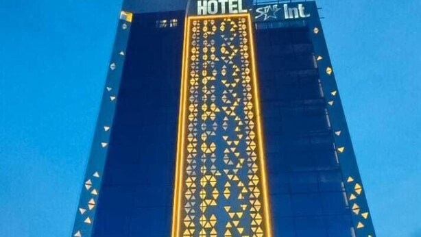 Un grand immeuble d’hôtel, doté d’un éclairage vertical bien visible et d’une enseigne indiquant « HÔTEL ».