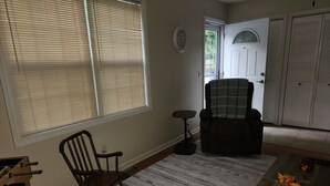 A living room with a rocking chair, a coffee table with a sunflower decoration, and a door with a window. - Quiet and sophisticated apartment with AC in Clinton (Clinton)