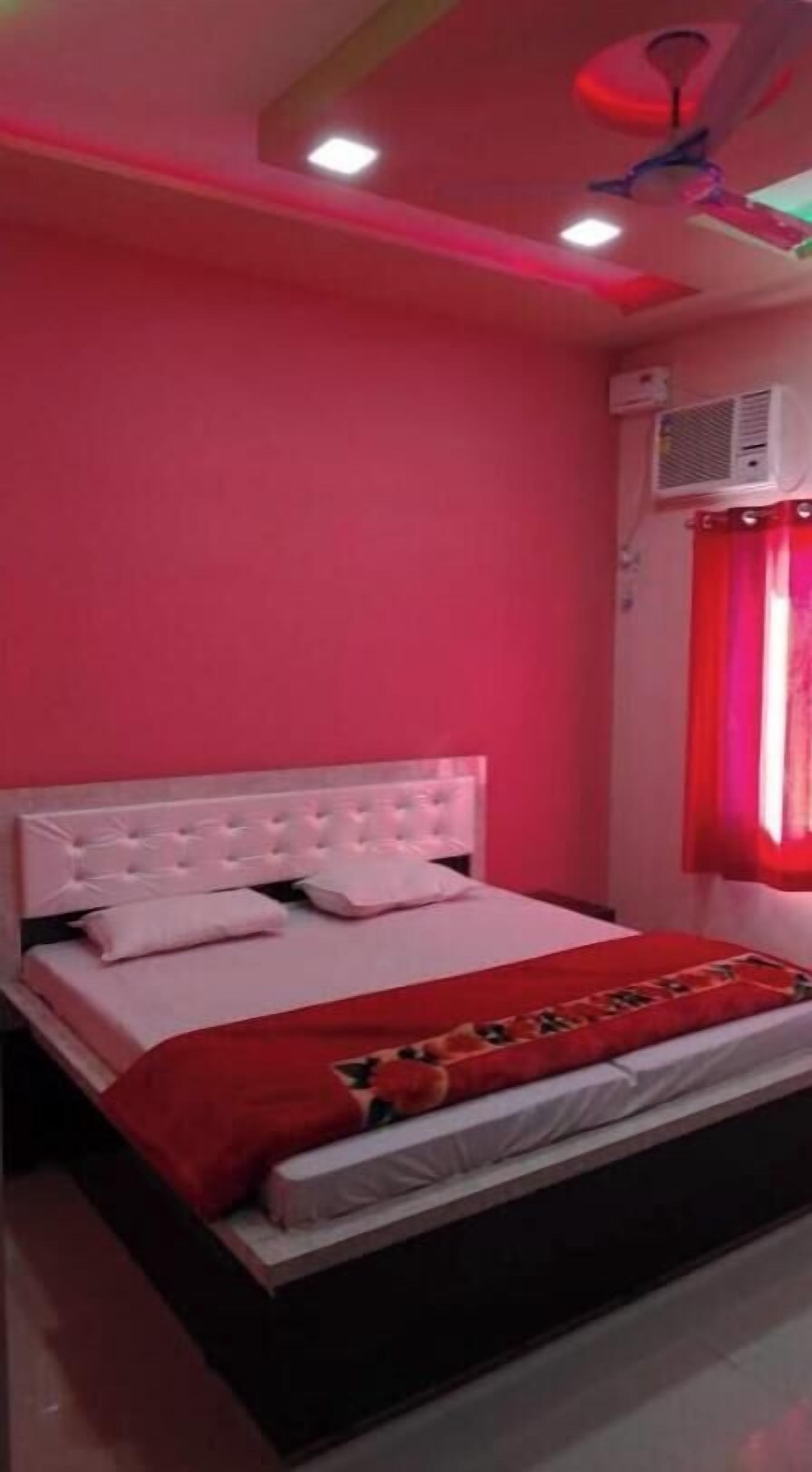Une chambre à coucher avec un lit blanc, des murs rouges et un ventilateur de plafond.