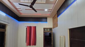 Une pièce avec un ventilateur de plafond, un rideau rouge, une porte et un miroir.