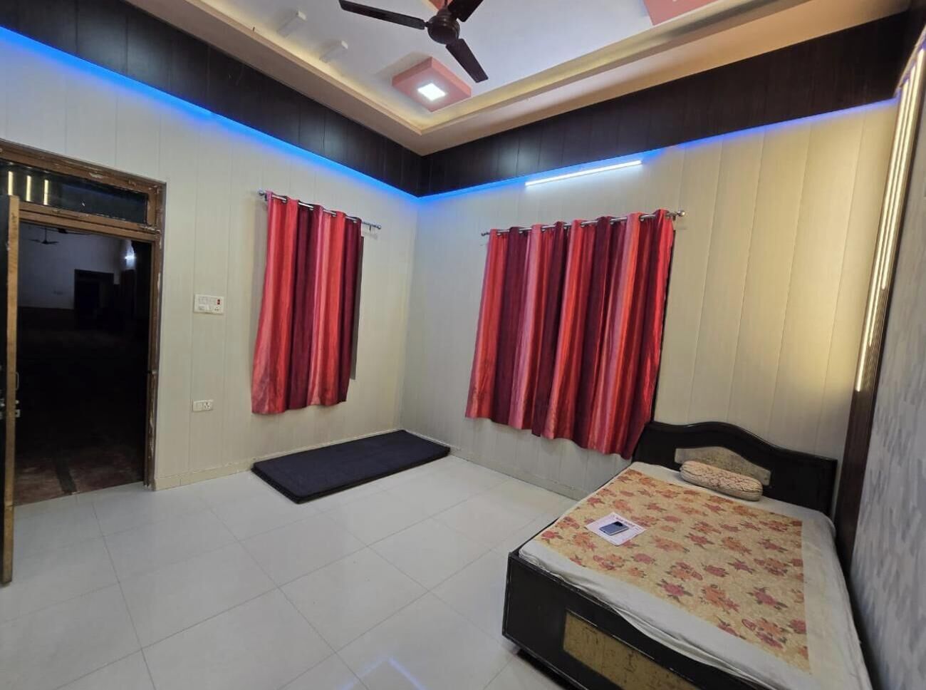 Une chambre à coucher avec un lit, un ventilateur de plafond et des rideaux rouges.