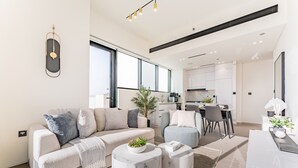 Una sala de estar moderna con un sofá, dos mesitas de mármol y un comedor con sillas y una mesa.