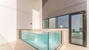 Un interior moderno con piscina envuelta en cristal, puerta corredera de vidrio y diseño minimalista.