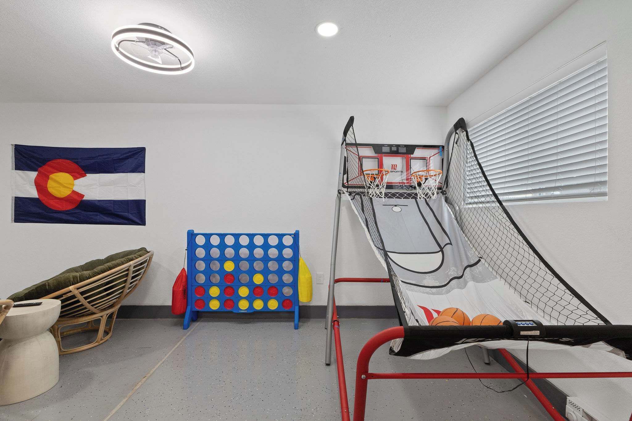 Ein Basketballfeld mit Korb, einem blau-roten Spielbrett, einem Korbstuhl und einer Flagge an der Wand.