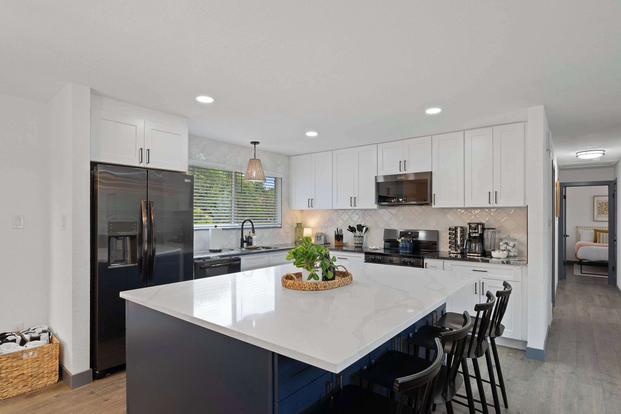 A modern kitchen with white cabinetry, a large island, and a built-in microwave.