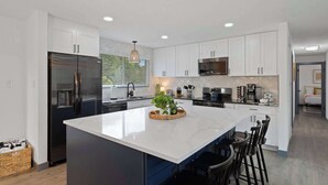A modern kitchen with white cabinetry, a large island, and a built-in microwave.