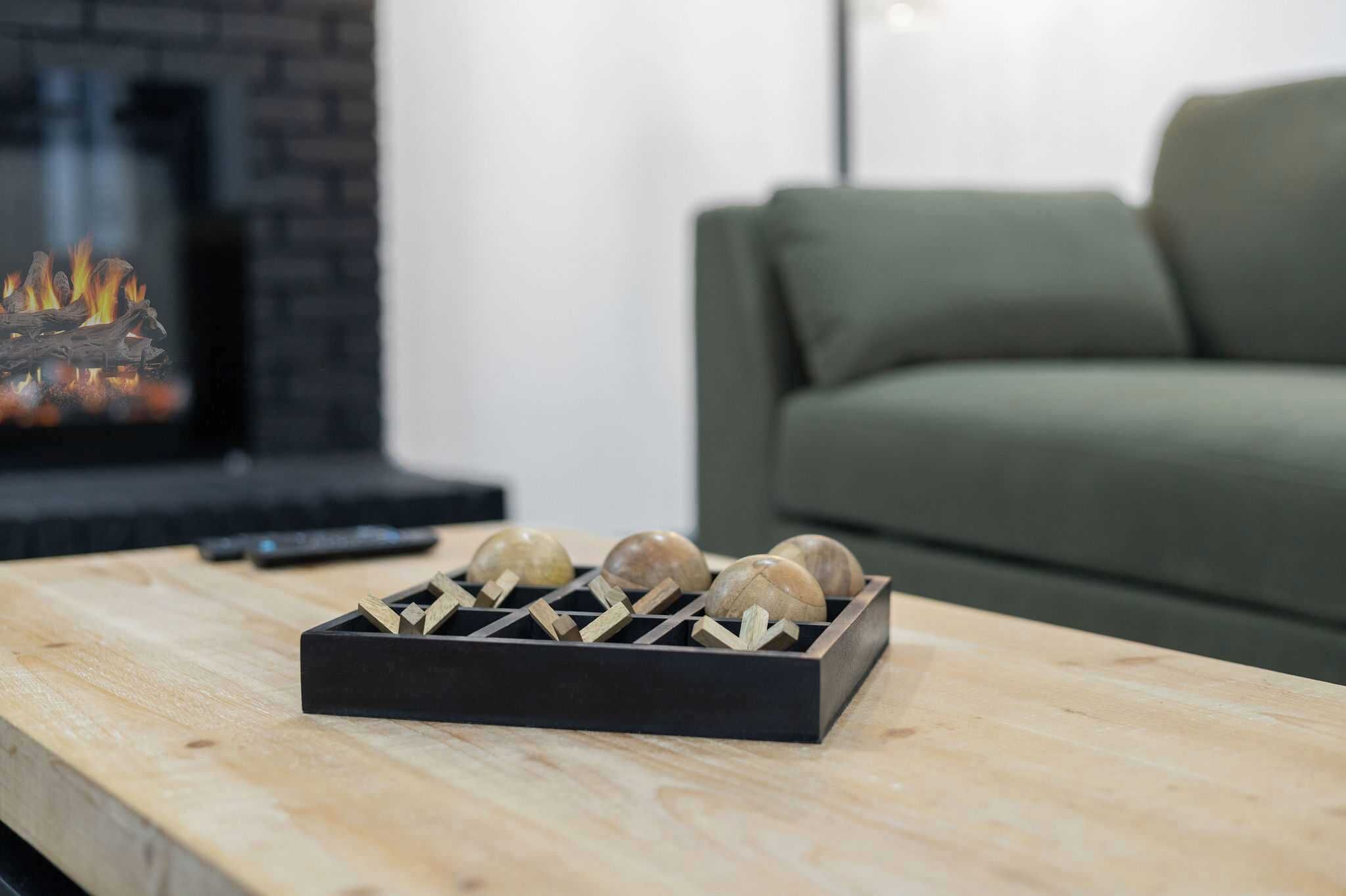 A wooden tray with spherical objects on a table, a remote control, and a sofa in the background.