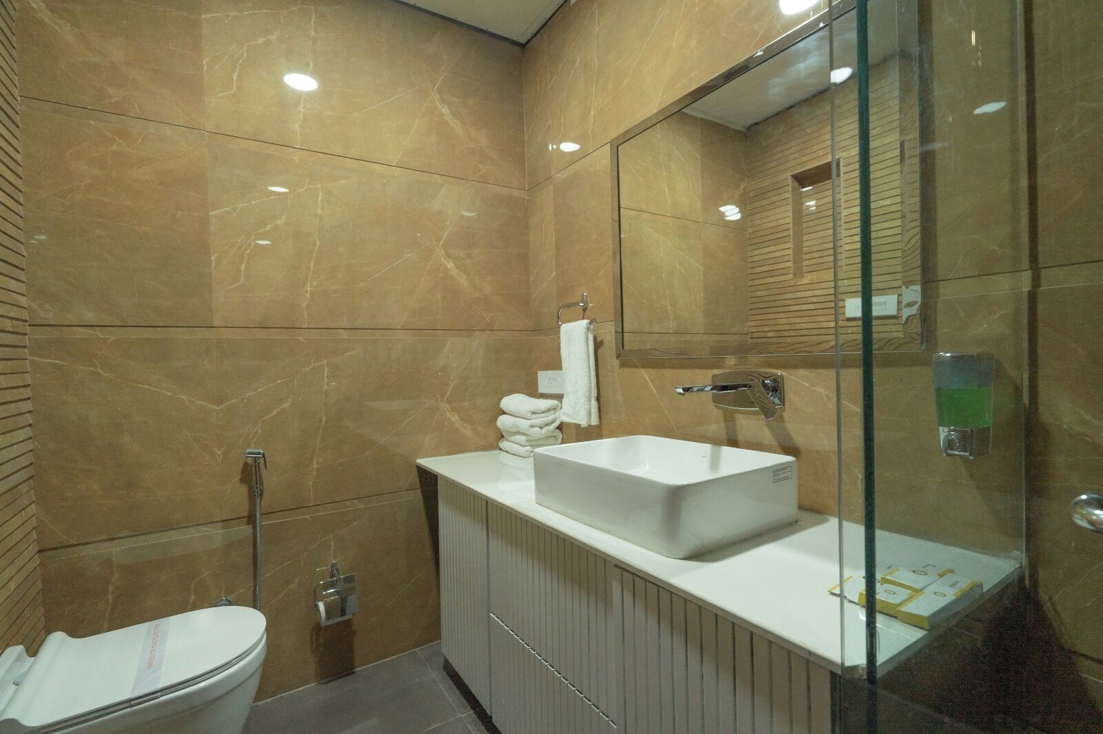 A modern bathroom with a large mirror, a white sink, and a glass shower enclosure.