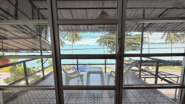 A room with a large window overlooking a beach with chairs and a blue car. - Moonlight Bar and restaurant  (Koh Samui)