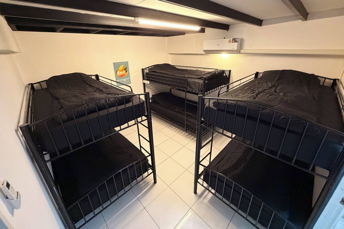 Un dormitorio con tres literas, un ventilador de techo y un cartel en la pared.
