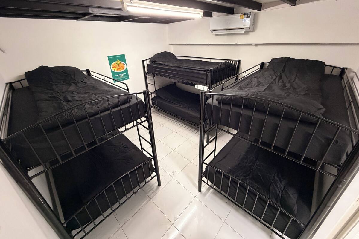 Un dormitorio con literas, un cartel en la pared y un equipo de aire acondicionado.