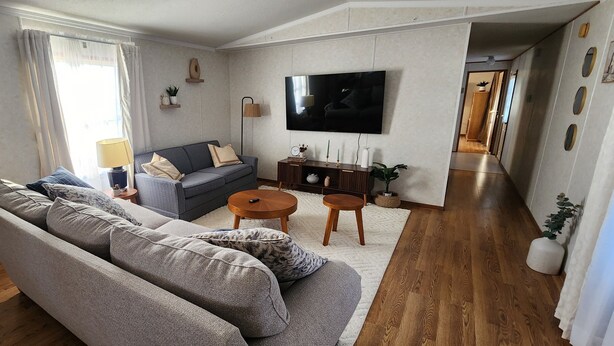 A modern living room with a grey sofa, a small round table, and a flat-screen TV mounted on the wall. - Family Getaway in Interior, SD – Just 5 Min to Badlands NP (Interior)
