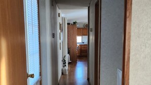 A hallway with a wooden door on the left, a white wall, and a ceiling light. - Family Getaway in Interior, SD – Just 5 Min to Badlands NP (Interior)