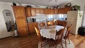 A kitchen with wooden cabinets, a dining table with chairs, a refrigerator, and a window. - Family Getaway in Interior, SD – Just 5 Min to Badlands NP (Interior)