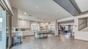 A modern kitchen with a central island, stainless steel appliances, and a view to the living area. - Luxury 2 Story 3 Car Garage Home (Las Vegas)