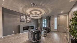 A spacious living area with a fireplace, a round coffee table, and a large plant. - Luxury 2 Story 3 Car Garage Home (Las Vegas)