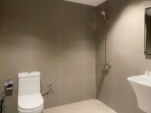 A modern bathroom with a toilet, shower, and sink.