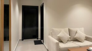 A modern living room with a sofa, a coffee table, and a black door. - Arjan Park Apartments (Riyadh)