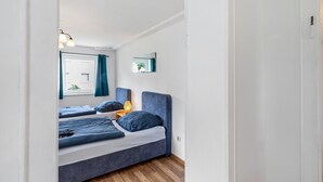 A bedroom with two beds, a window with curtains, a bedside lamp, and a mirror on the wall. - Apartment 'Yellow A' (Miltenberg)