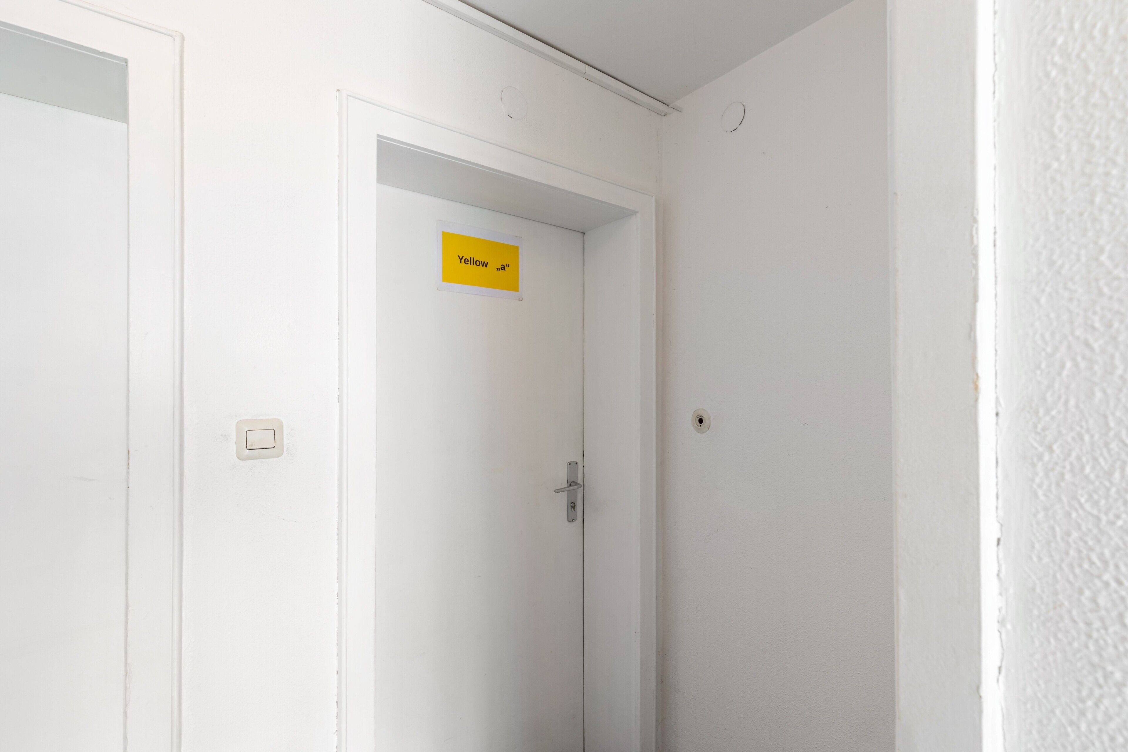 Een witte deur met een geel bord waarop 'Yellow' staat en een sleutelgat.