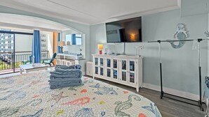 A hotel room with a large bed, a TV mounted on the wall, a balcony with a view, and a white cabinet with glass doors. - Oceanfront Resort Condo with Balcony (Myrtle Beach)