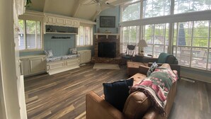 A spacious living area with a fireplace, seating, and large windows.