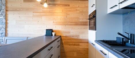 Une cuisine moderne avec un plancher en bois, des armoires blanches et un comptoir en granit.
