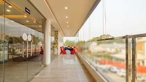 A corridor with glass walls, a pull station, and a view of a road with orange barriers. - Treebo KGF Villa with Swimming Pool (Prayagraj)