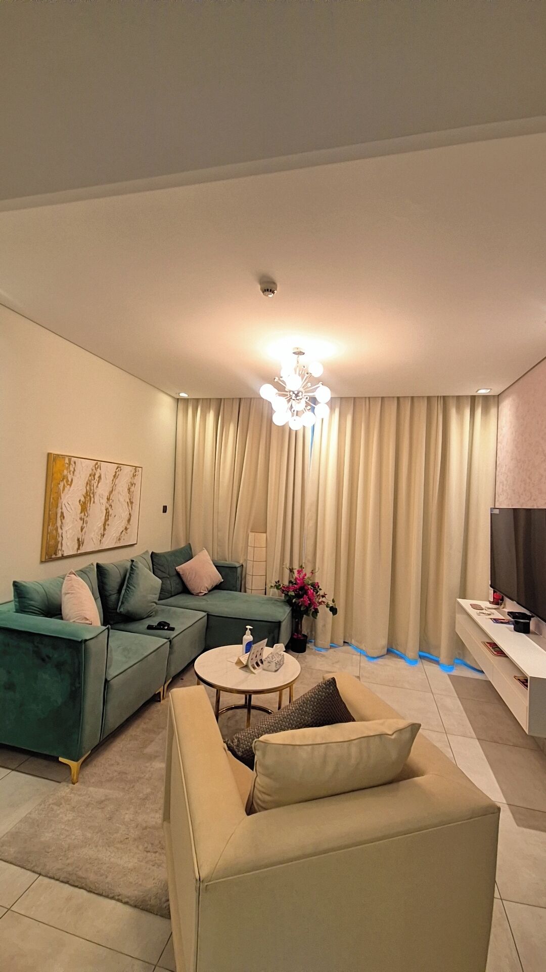 Una sala de estar moderna con un sofá seccional, una mesa de centro redonda y un televisor de pantalla plana.