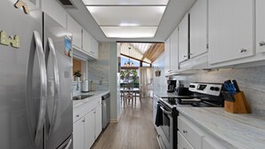 A modern kitchen with stainless steel appliances, white cabinetry, and a marble countertop.