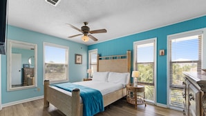 A bedroom with a bed, a ceiling fan, a nightstand, a dresser, and a window with blinds.
