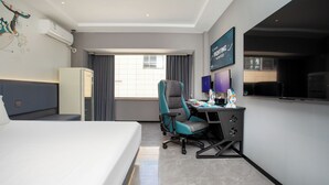 A hotel room with a bed, a desk with a computer, a chair, an air conditioner, a TV, and a window with curtains. - E-sports Wanyoo Hongkou  Shanghai (Shanghai)