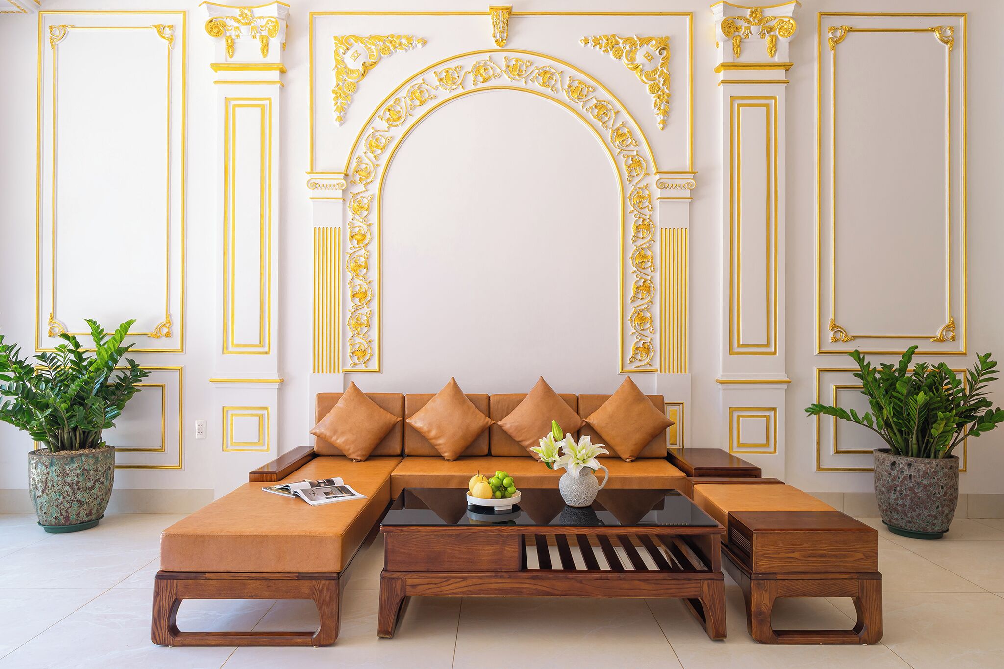 A modern living room with a sectional sofa, coffee table, and decorative plants.