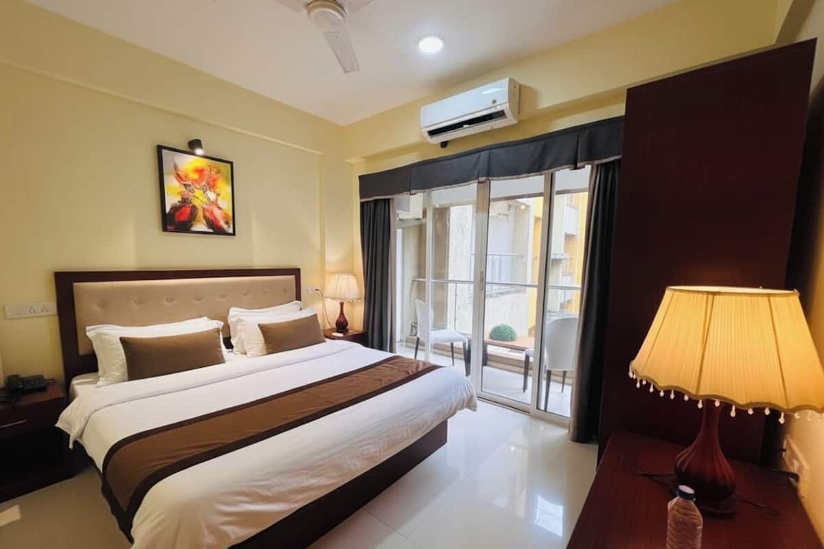 Une chambre d’hôtel avec un grand lit, une table de chevet, une lampe, un climatiseur et une vue sur l’extérieur.